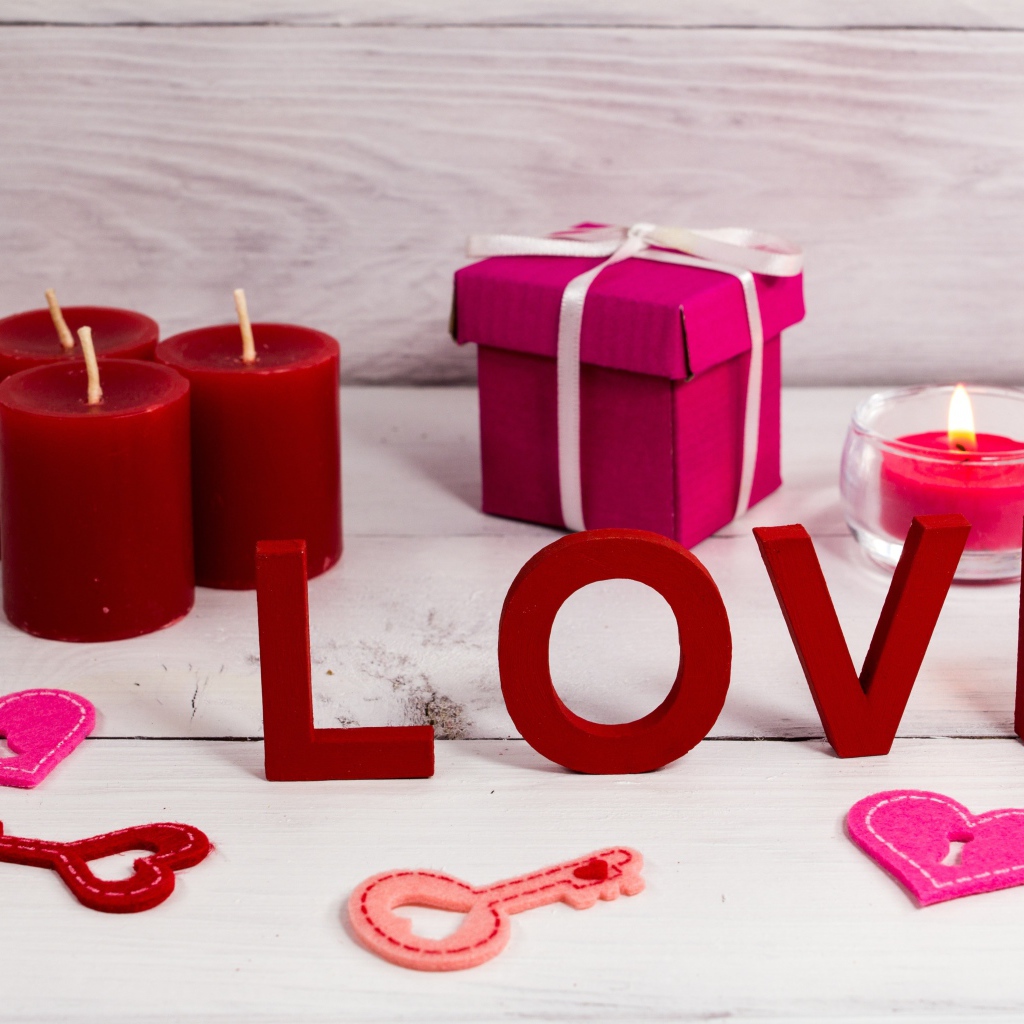 Надпись любовь на столе с красными свечами и подарком