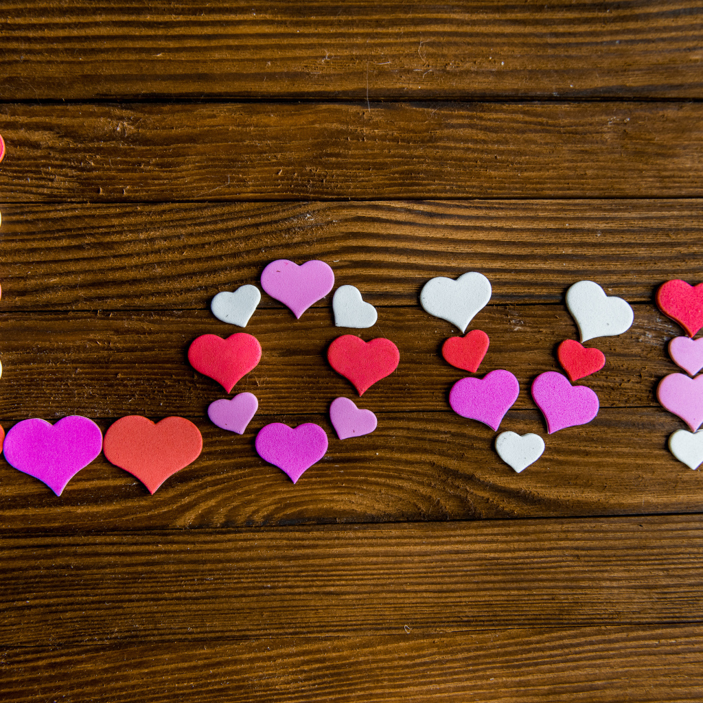 Надпись любовь из разноцветных сердец на деревянном столе