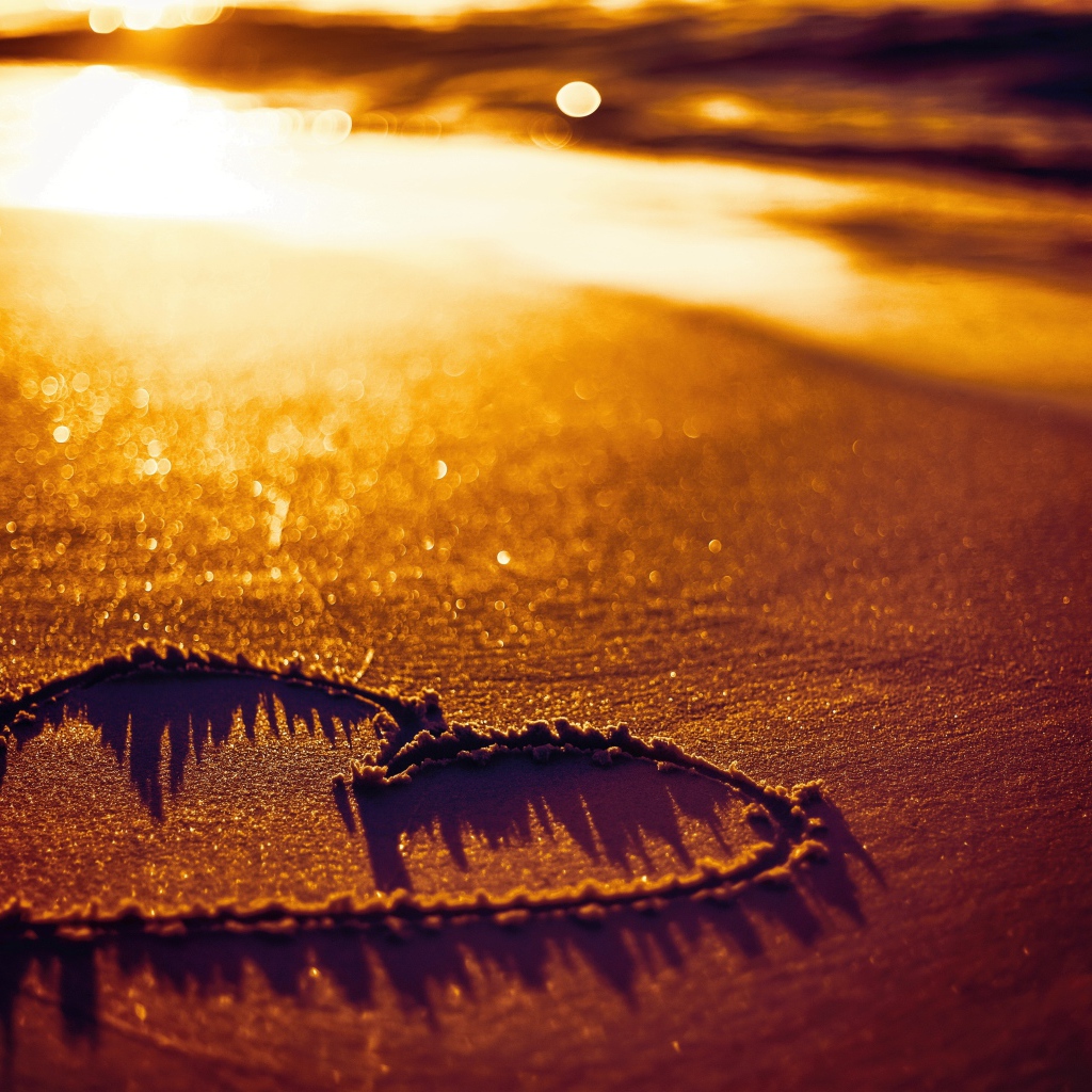 Нарисованное сердце на песке в лучах солнца
