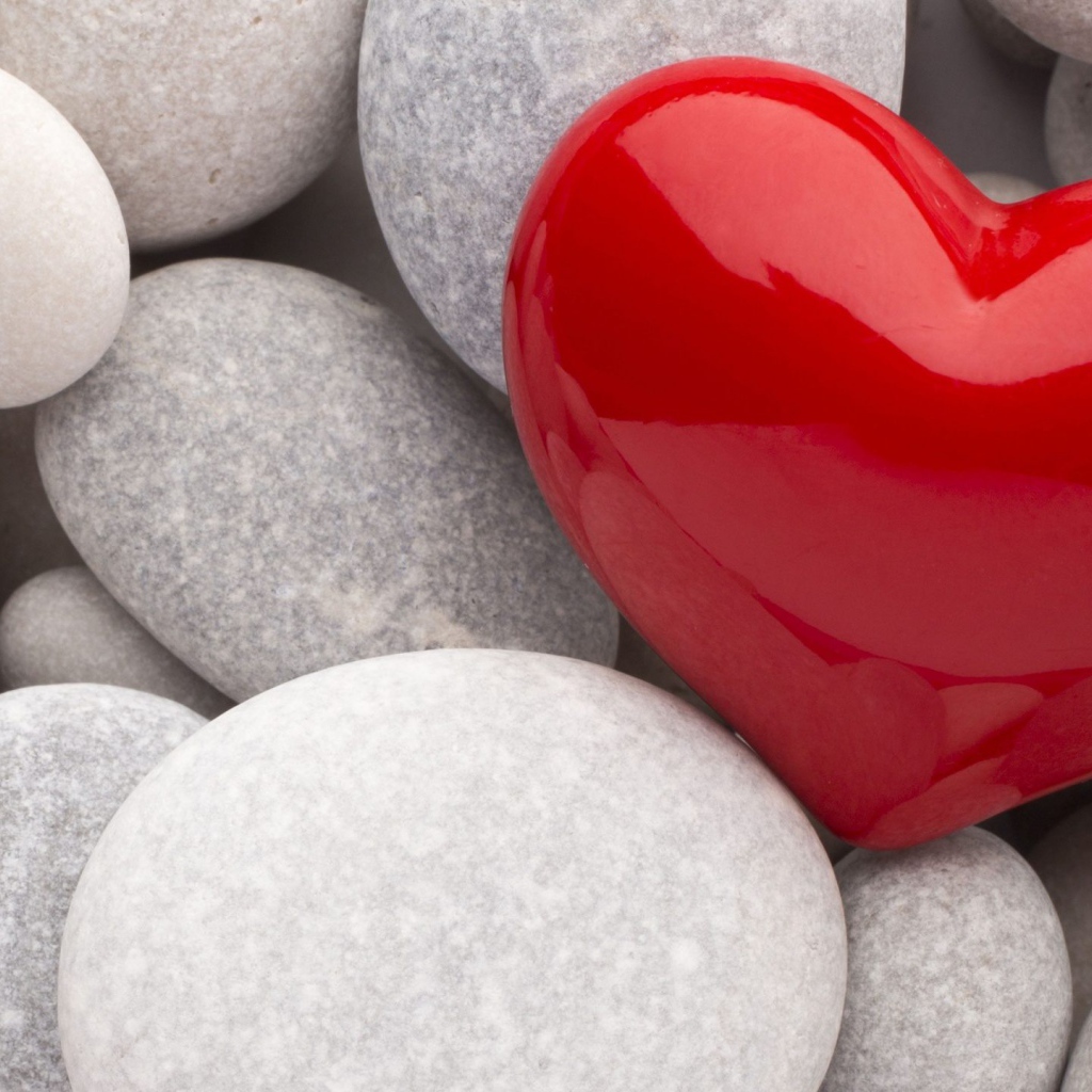Красное сердце лежит на серых камнях 
