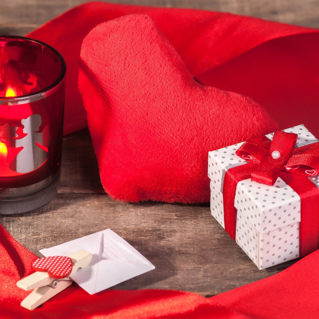 Мягкое красное сердце на столе с подарком и зажженной свечей