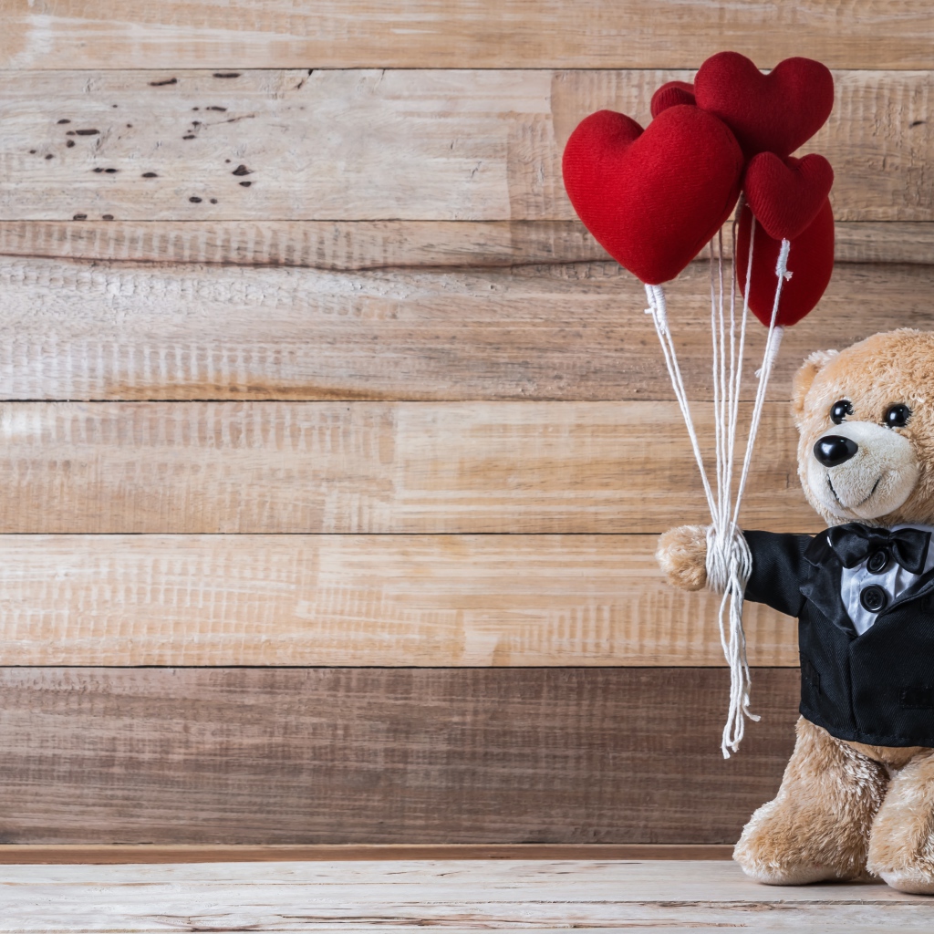 Плюшевый медведь с сердечками на деревянном фоне