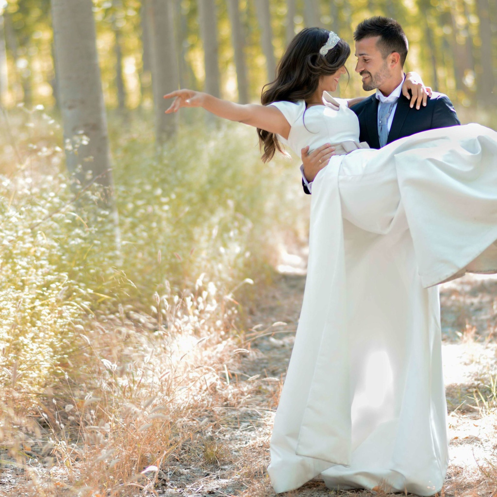 Парень жених держит на руках невесту в белом платье