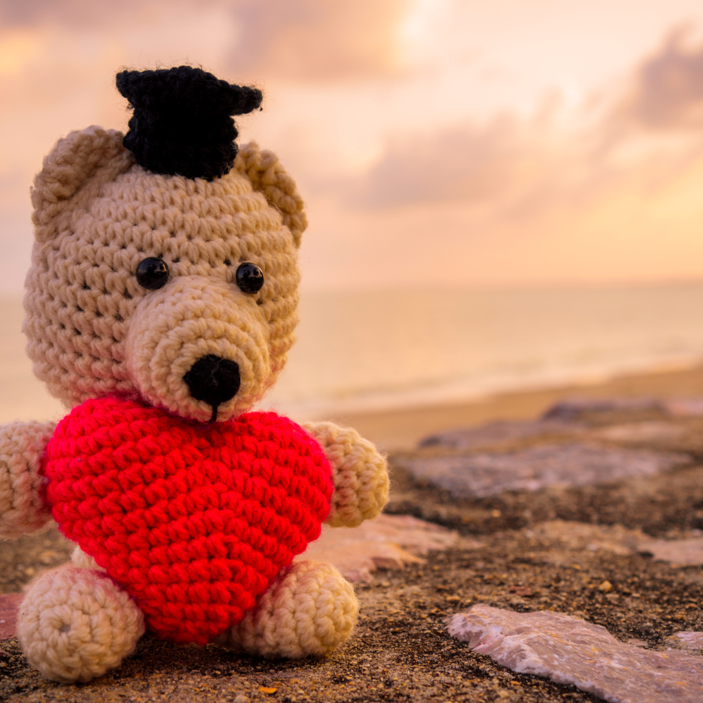 Игрушечный медведь с красным сердцем на фоне неба