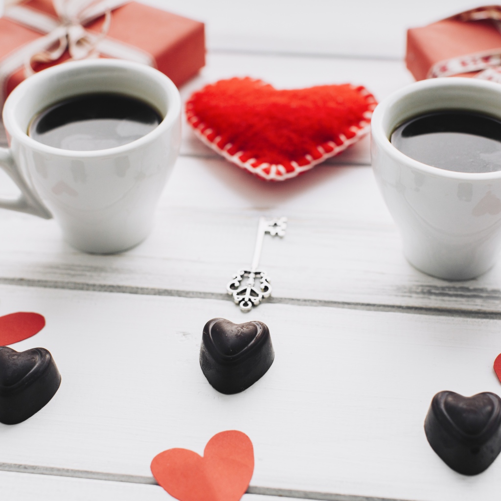 Две чашки кофе на столе с подарками, конфетами и сердечками