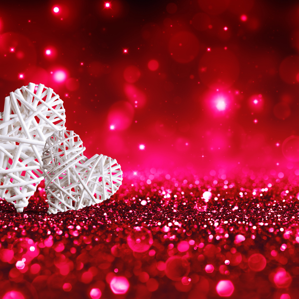 Два белых плетеных сердца на мерцающем красном фоне