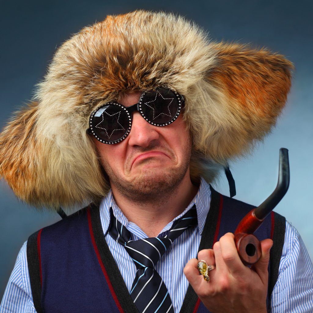 A man in a fur hat wearing fashionable glasses with a pipe in his hand
