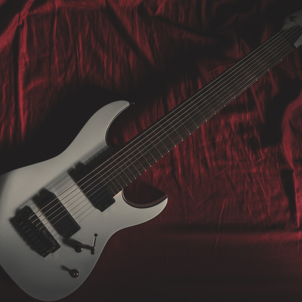 Гитара лежит на красном покрывале