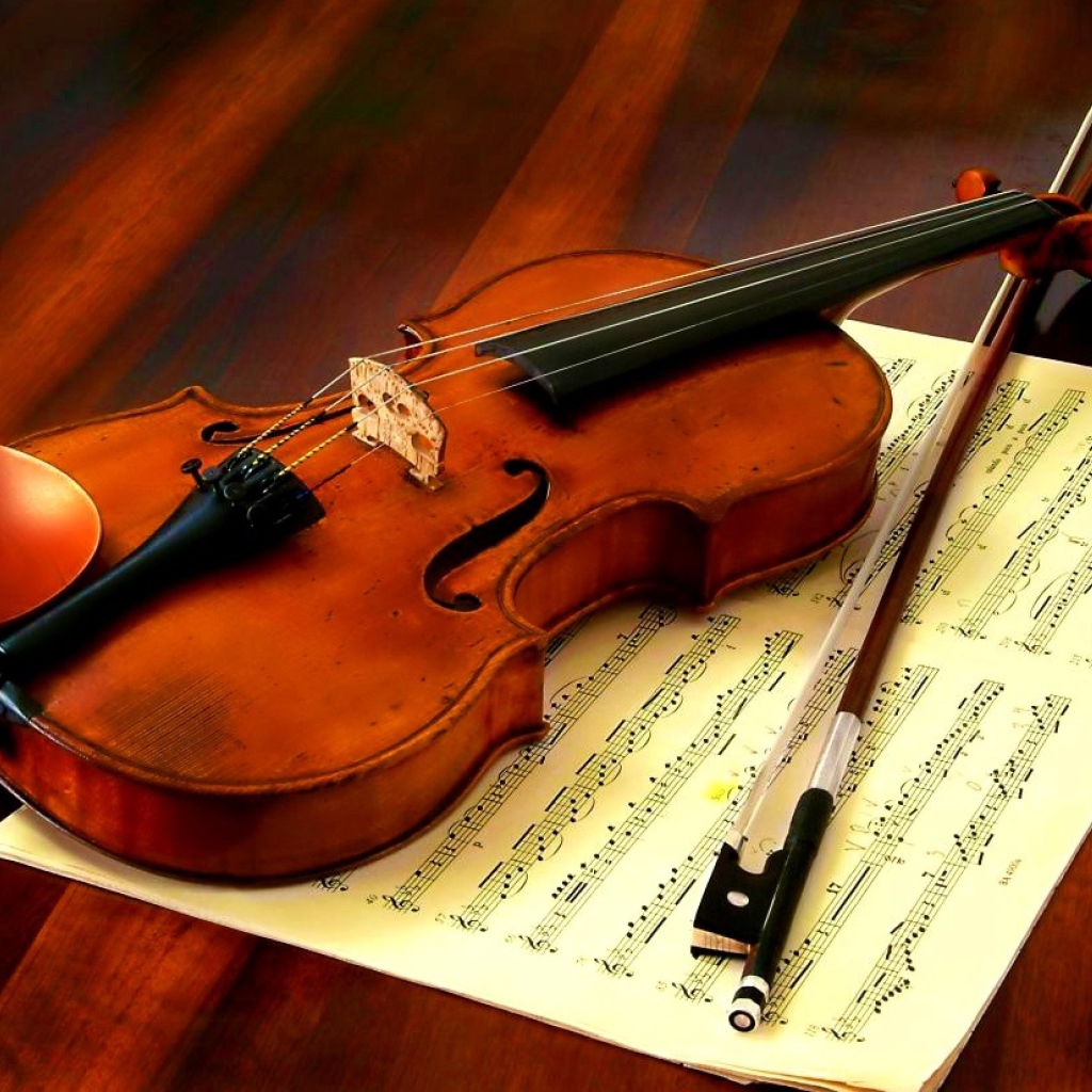 Скрипка со смычком лежат на нотной тетради