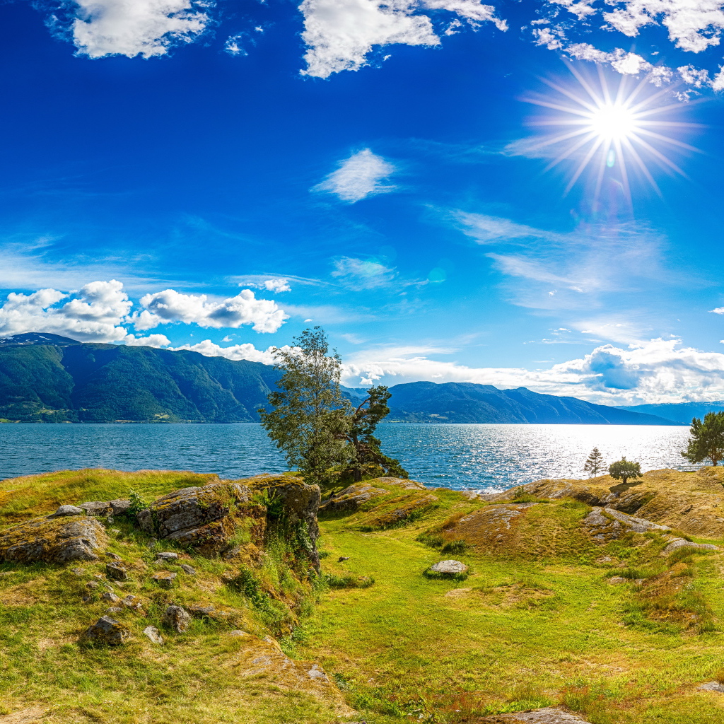 Красивое яркое солнце в голубом небе над горами и водой, Исландия