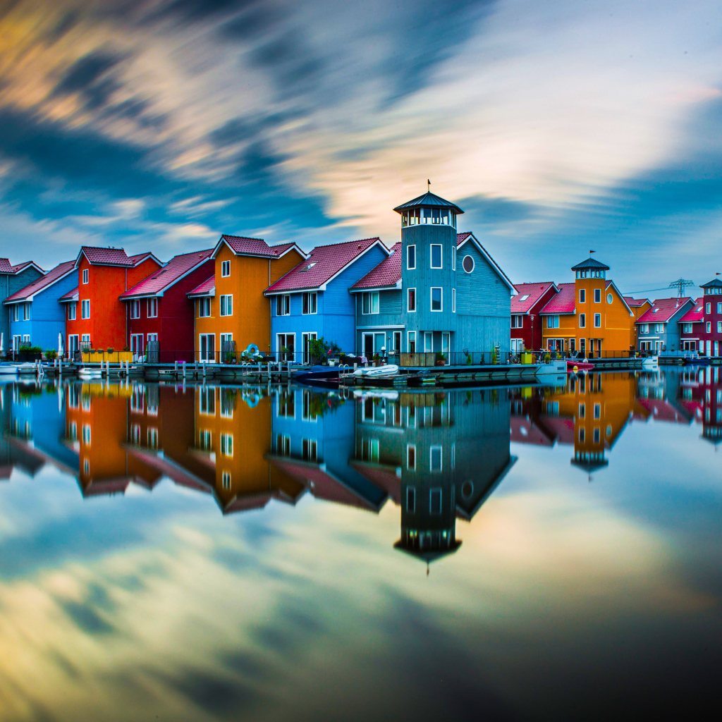Красивые разноцветные дома отражаются в воде под красивым небом