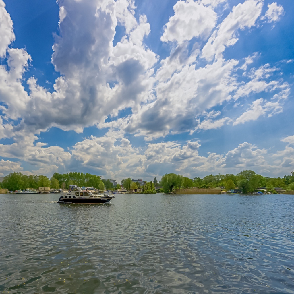 Катер на озере под красивым голубым небом с белыми облаками