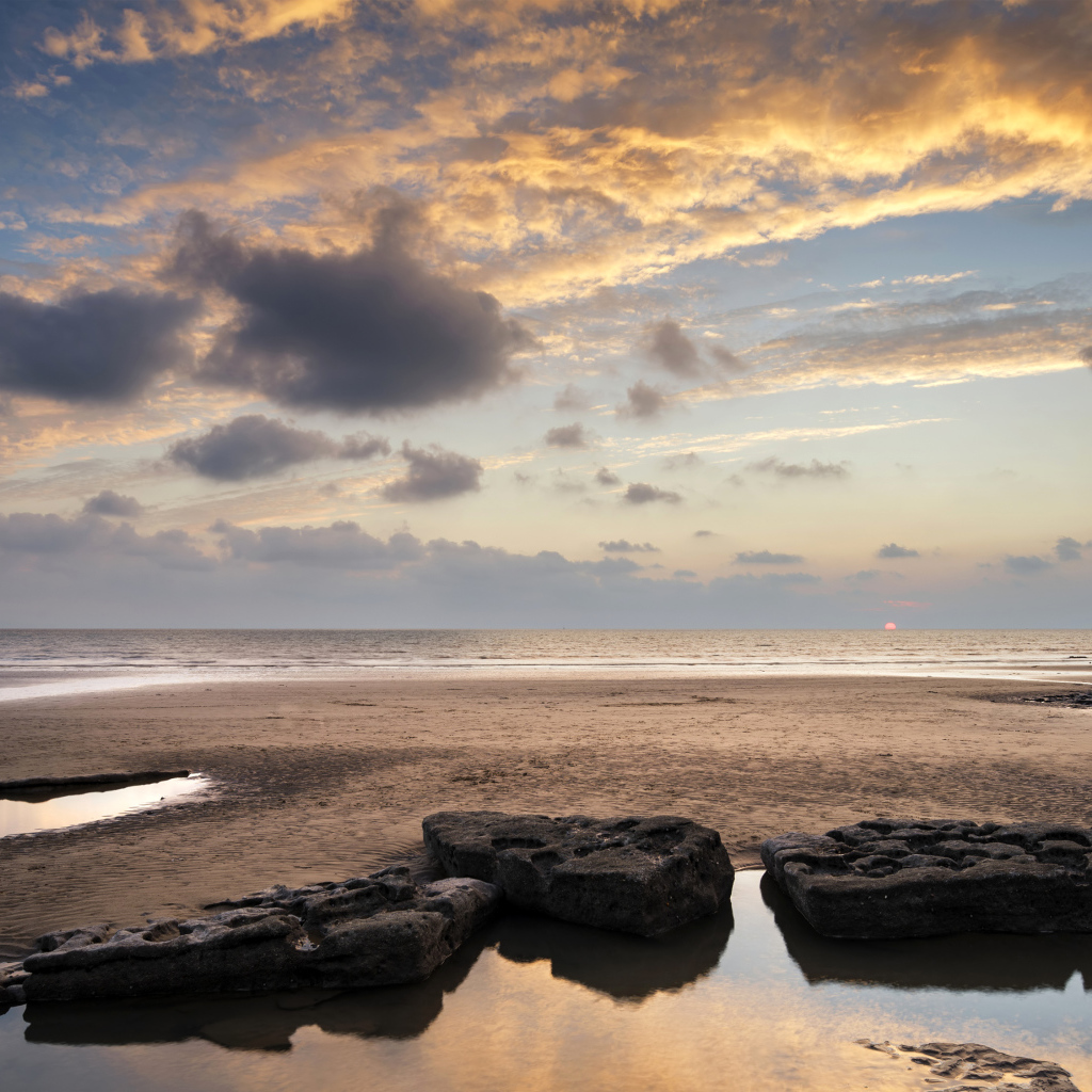 Большие камни в воде на песке под красивым небом