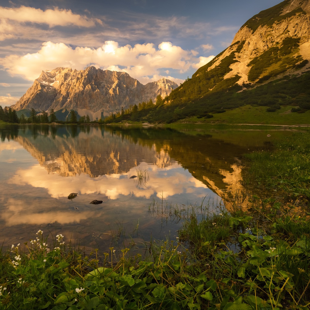 Горы в лучах солнца под красивым небом отражаются в воде