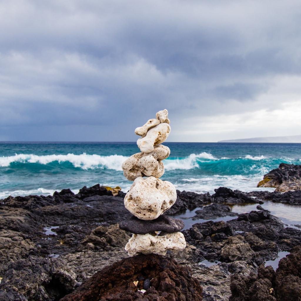 Пирамида из камней у моря на фоне пасмурного неба