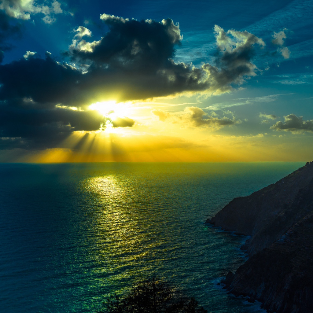Rays of bright sun make their way through the clouds above the sea
