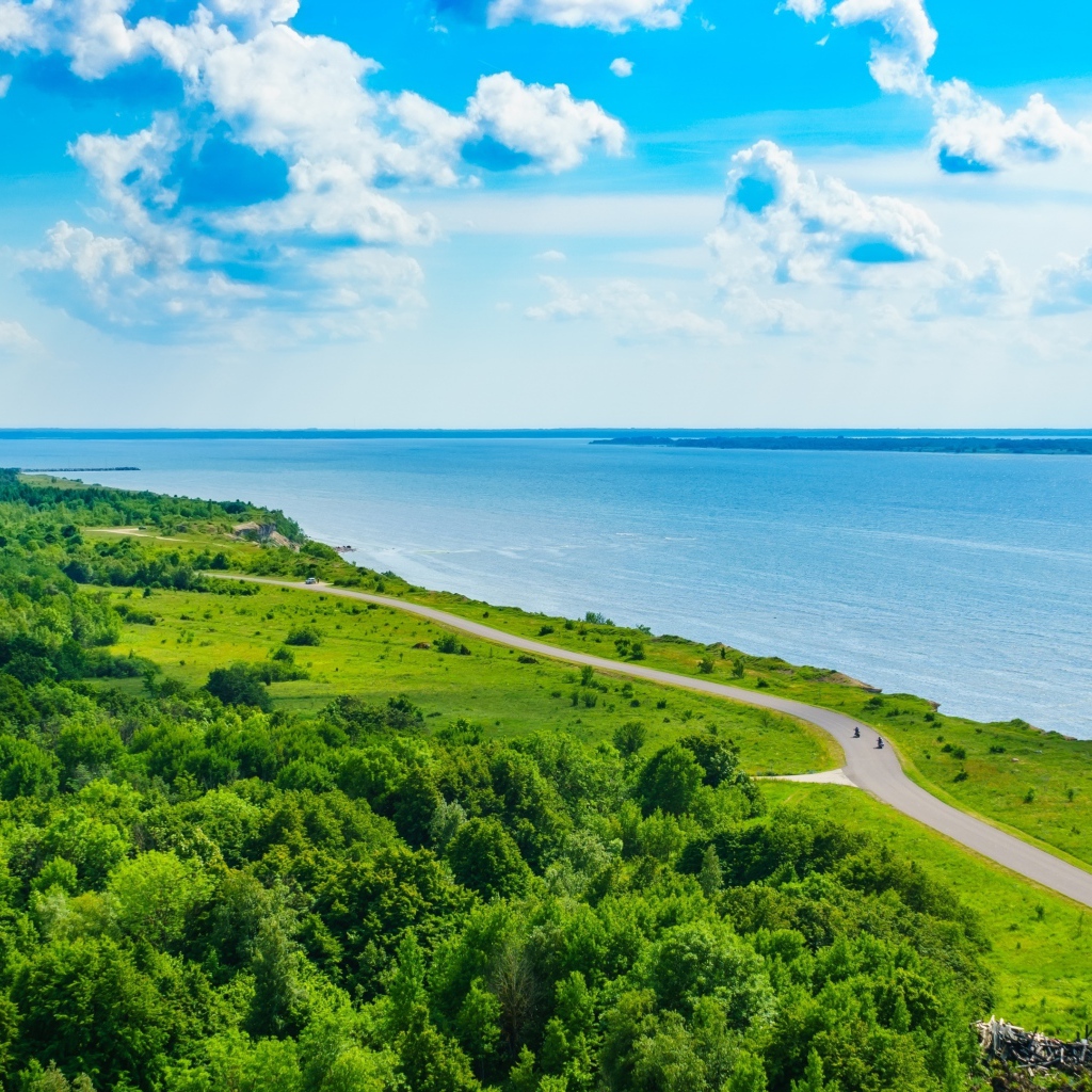 Дорога через побережье вдоль моря под голубым небом с белыми облаками