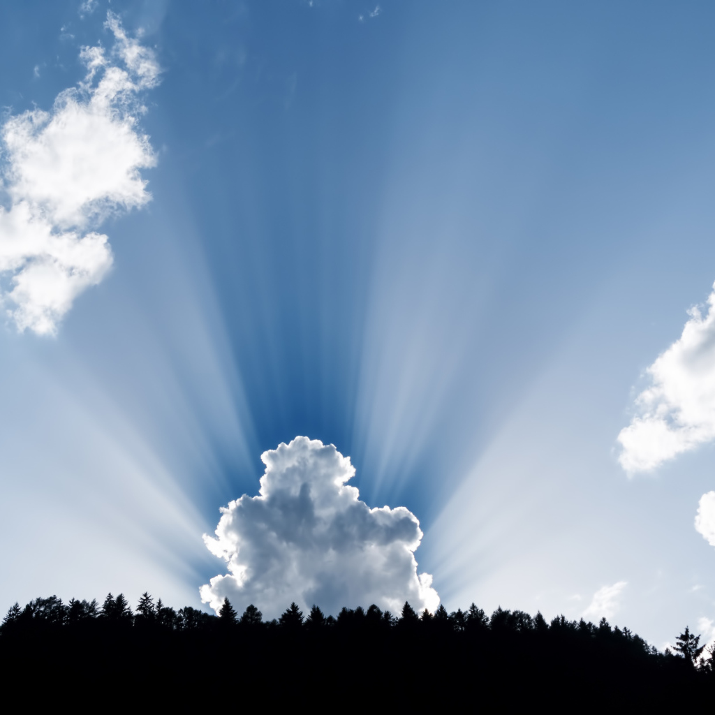 Лучи солнца пробиваются сквозь белые облака в голубом небе 