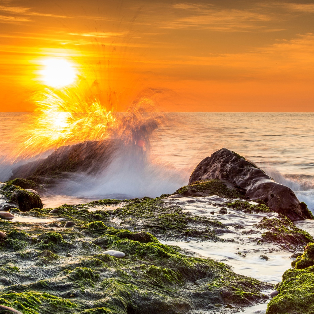 Бушующие волны в море бьются об камни на закате