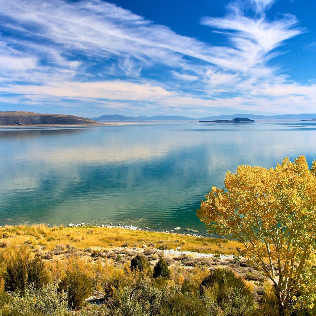 Белые облака в голубом небе отражаются в озере