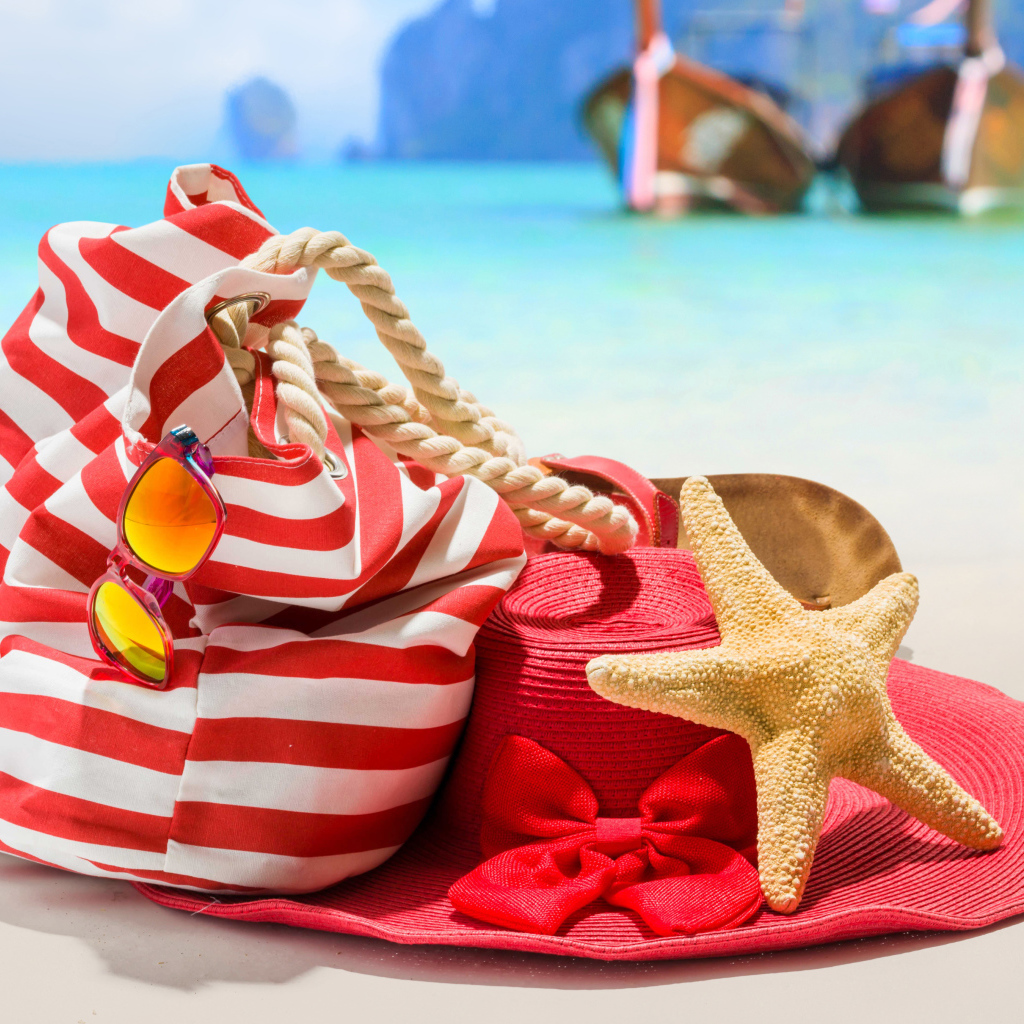 Большая красная шляпа с сумкой и морской звездой на пляже