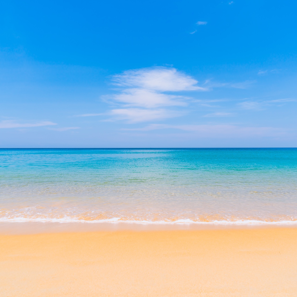 Желтый песок у лазурного океана под голубым небом