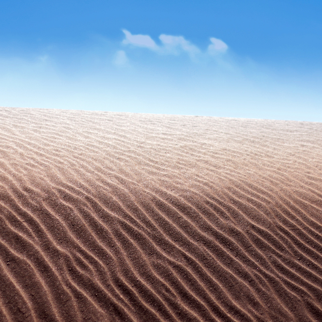 Песок в пустыне на фоне голубого неба