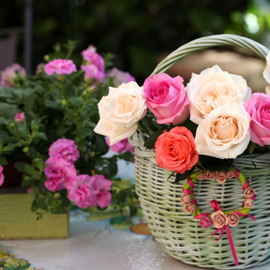 Букет нежных роз в корзине на столе с цветами