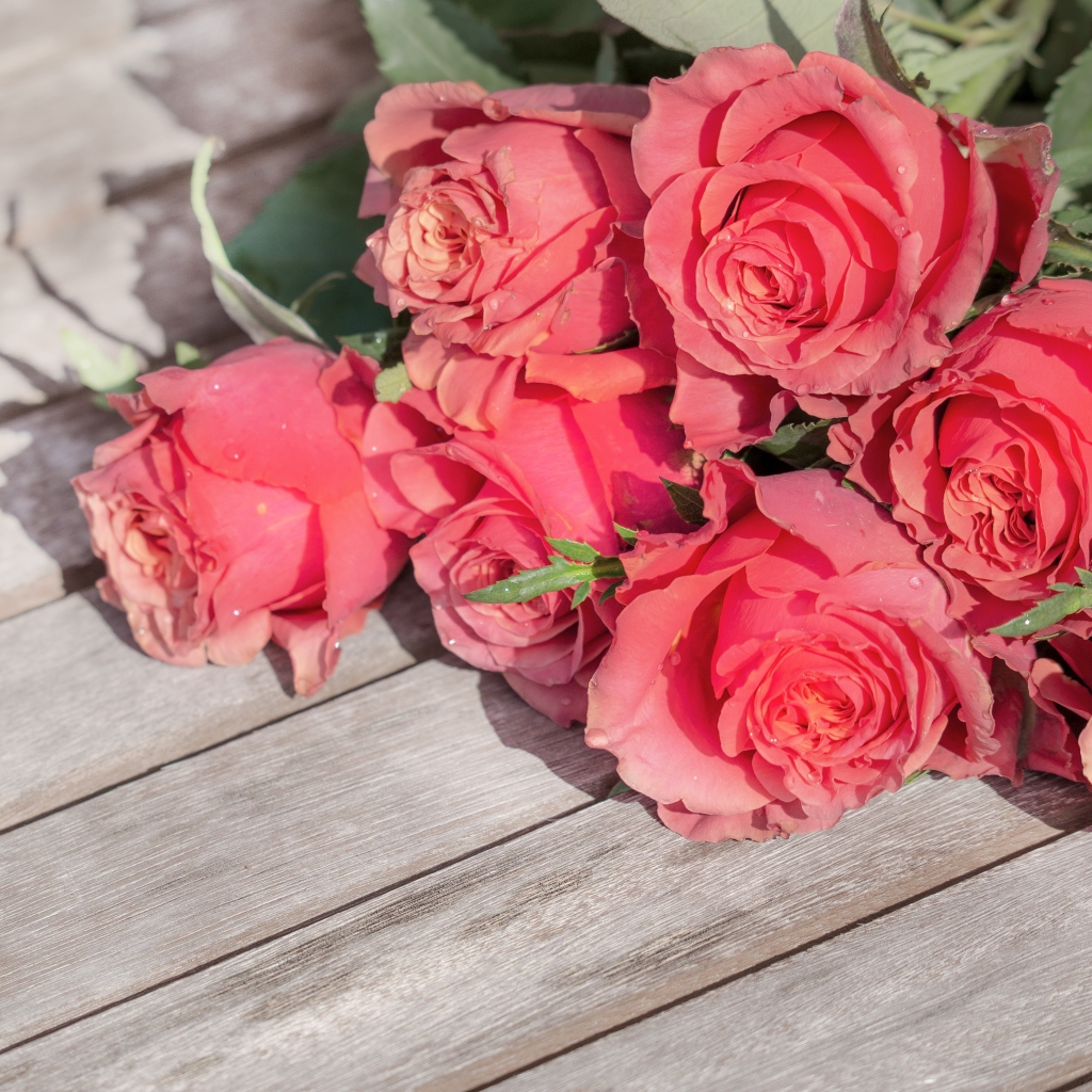 Букет розовых роз лежит на деревянной поверхности