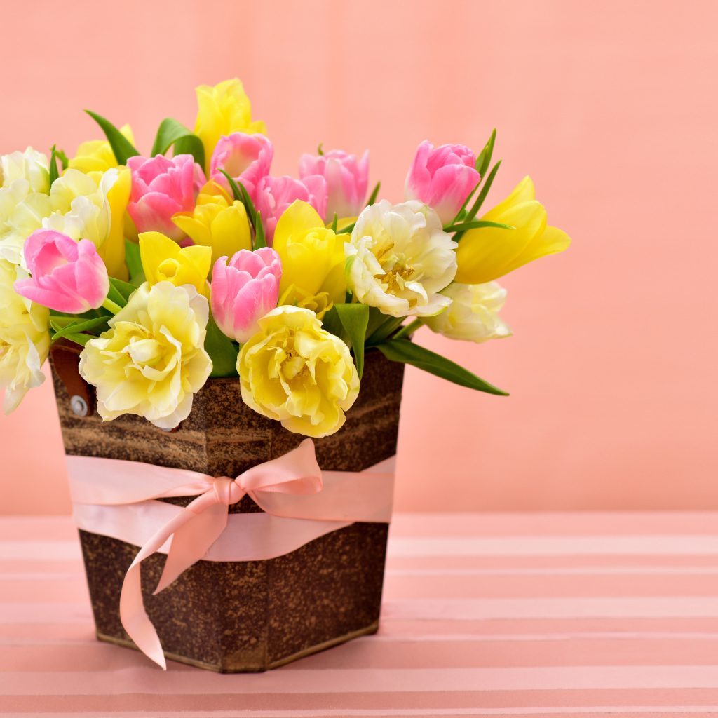 Букет красивых разноцветных тюльпанов в вазе на розовом фоне