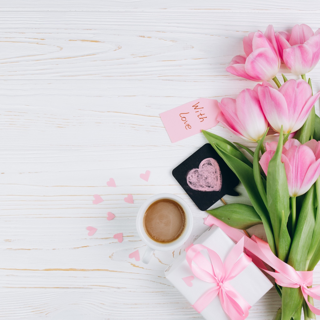 Букет розовых тюльпанов на столе с чашкой кофе и подарком 