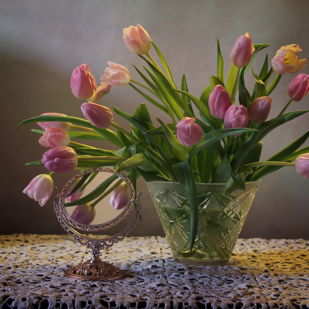 Розовые тюльпаны в стеклянной вазе на столе с зеркалом 