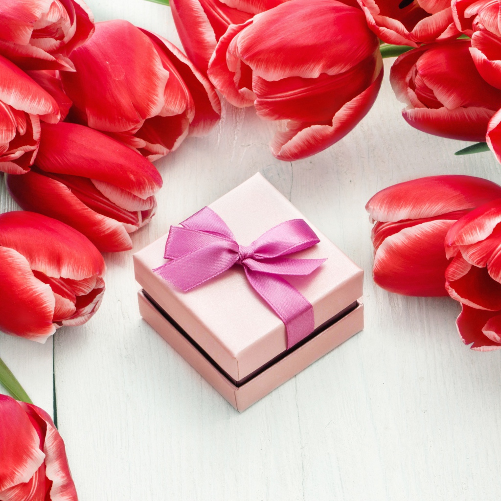 Красные тюльпаны на деревянной поверхности с подарком
