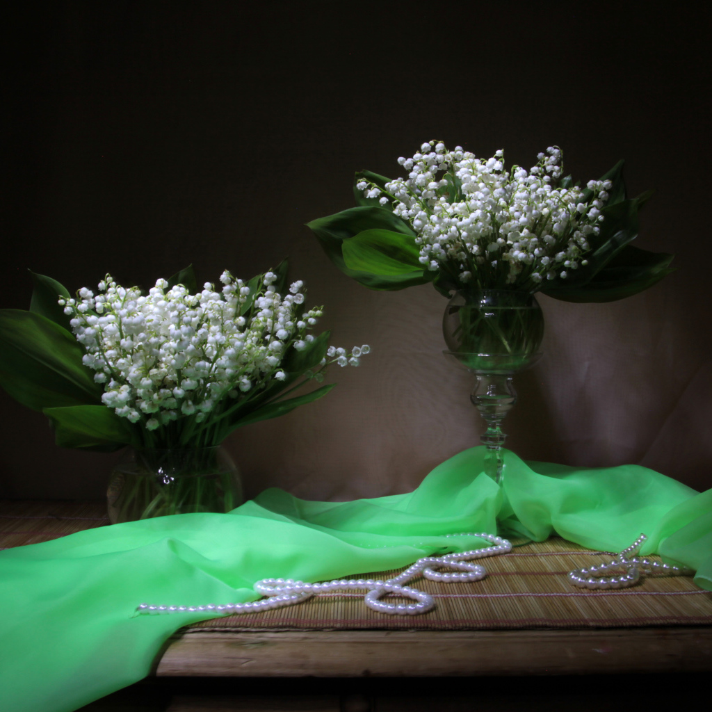 Два букета ландышей с бусами на столе 