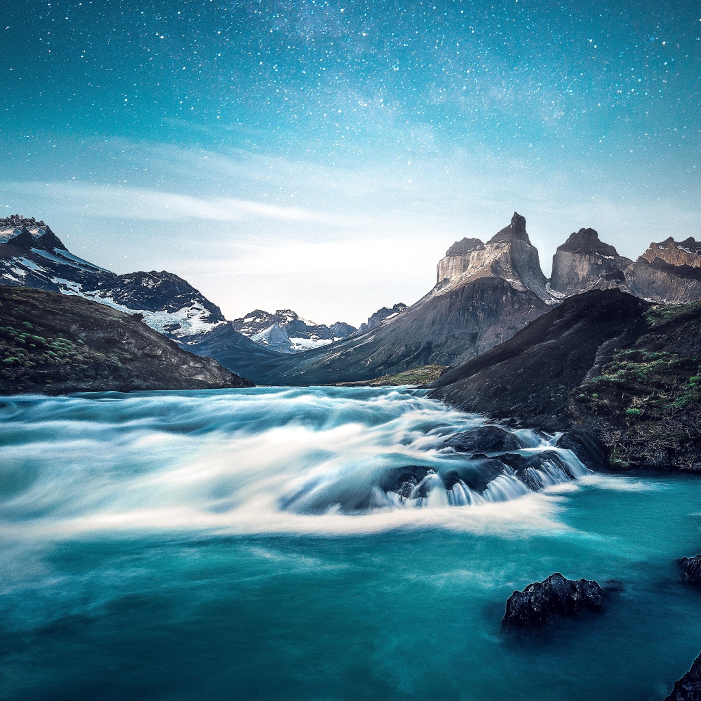 Быстрая вода к реке у гор на фоне голубого неба 