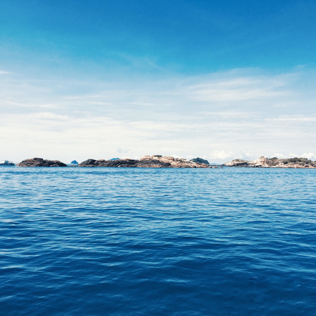 Спокойное синее море со скалами на горизонте