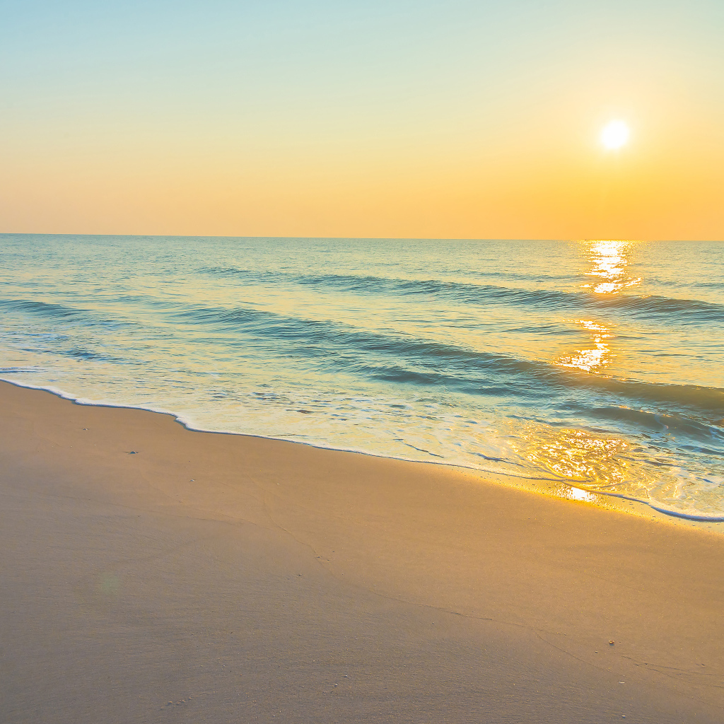 Морские волны на желтом песке на закате солнца летом