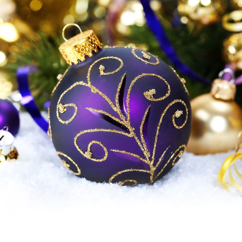 Красивая фиолетовая елочная игрушка лежит на снегу