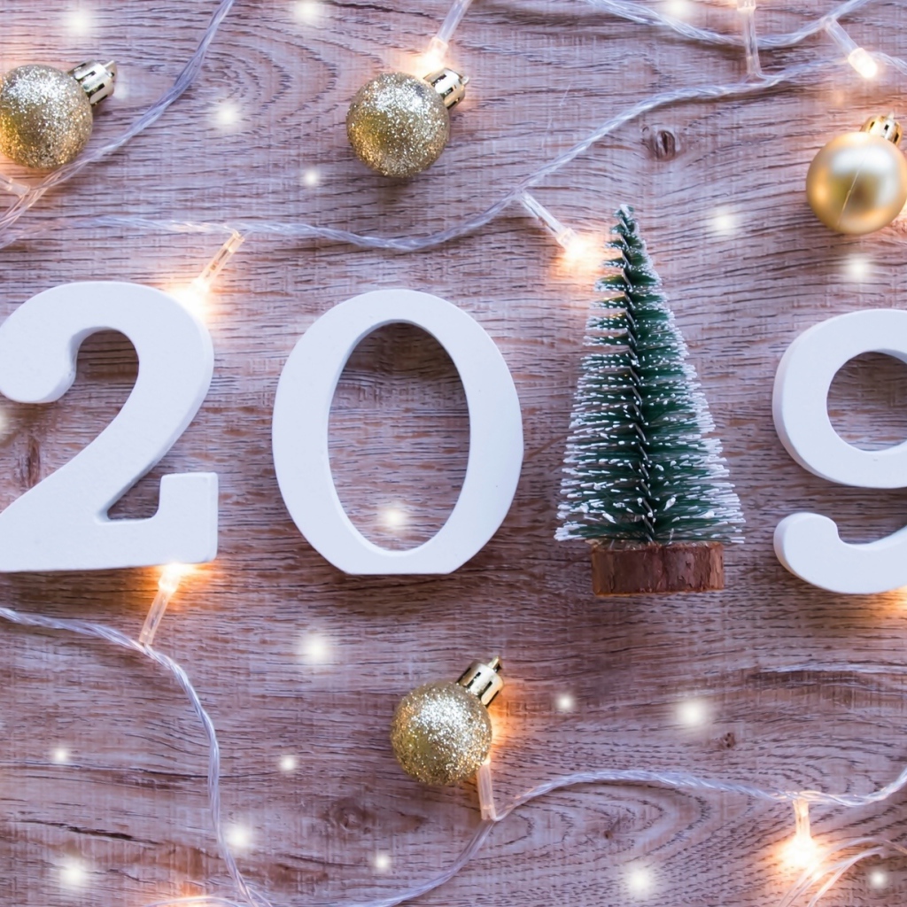 Цифры 2019 на деревянном фоне с елочными игрушками и гирляндой
