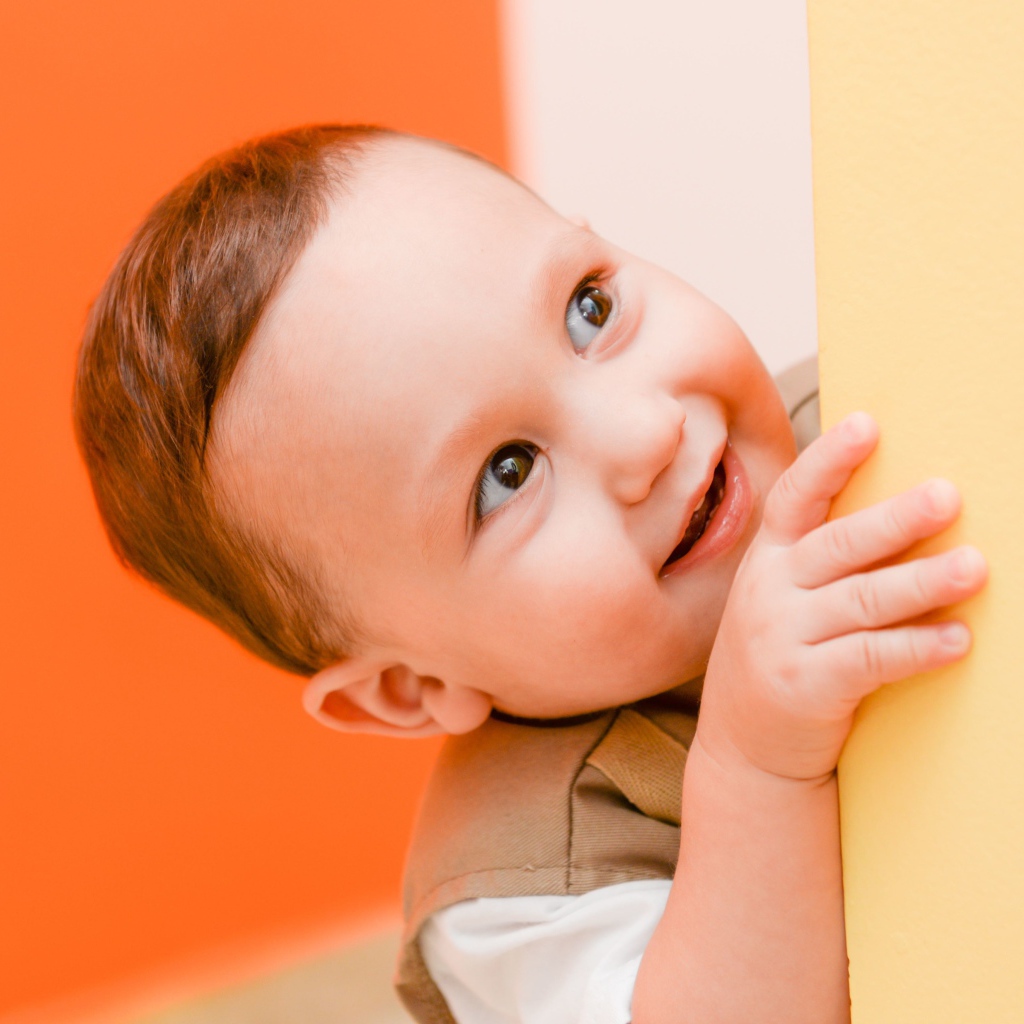 Маленький любопытный мальчик выглядывает из-за стены