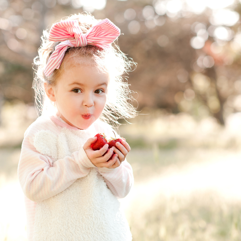 Милая маленькая девочка ест клубнику