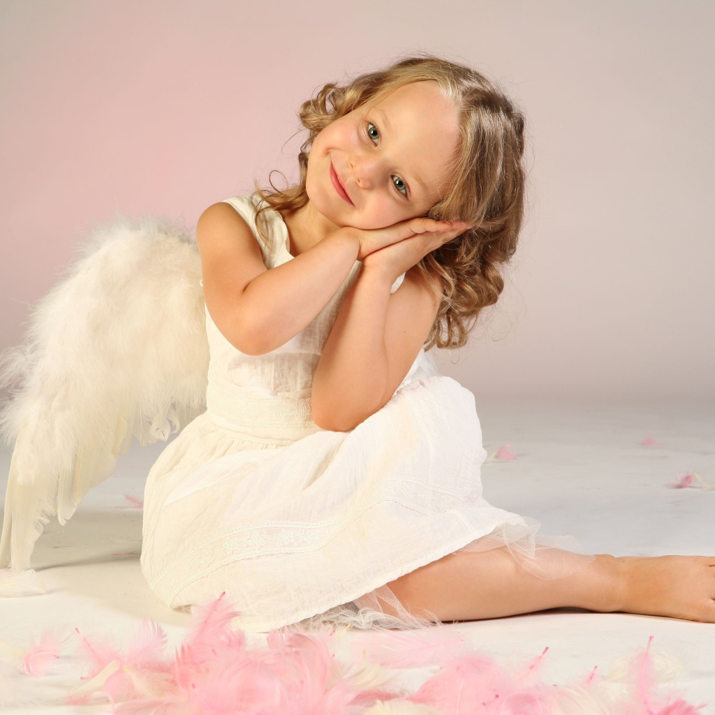 Милая маленькая девочка в белом платье с крыльями ангела