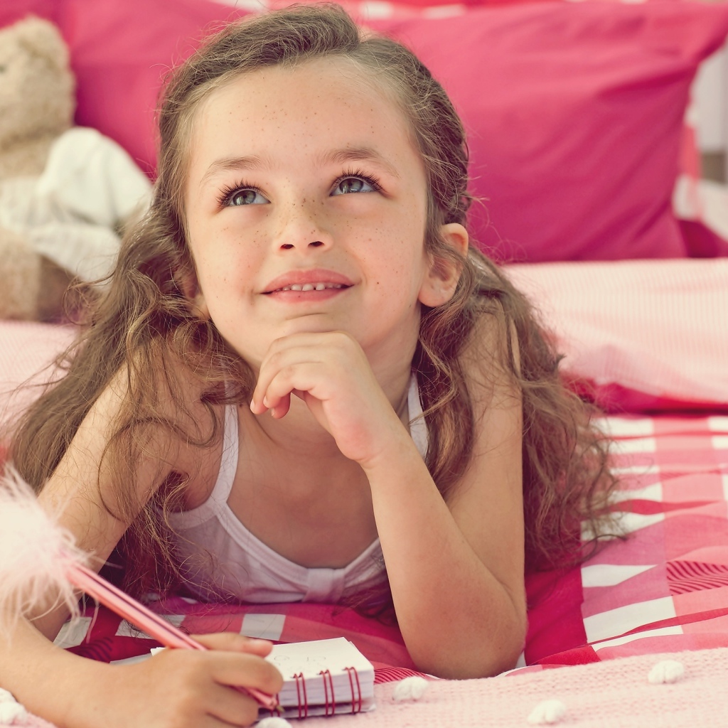 Замечтавшаяся маленькая девочка лежит на кровати