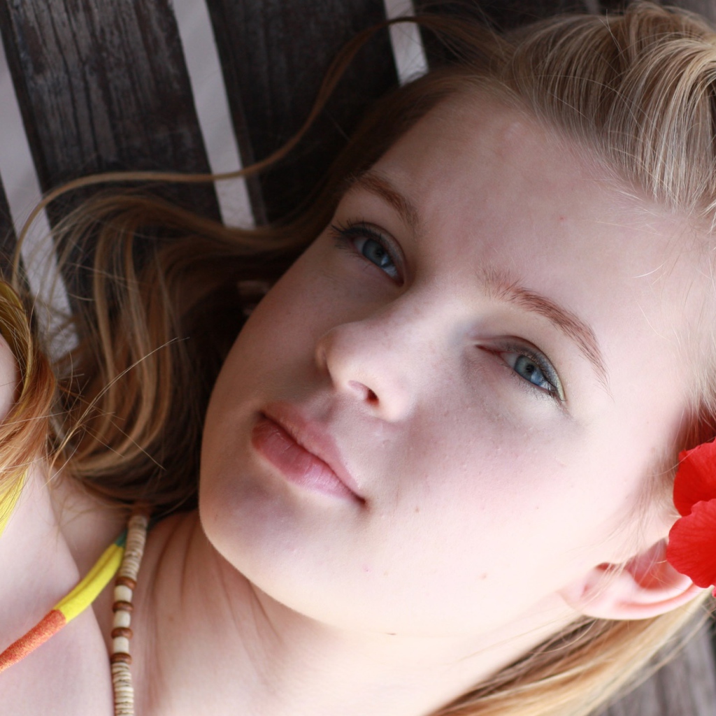 Девочка с красным цветком гибискуса в волосах