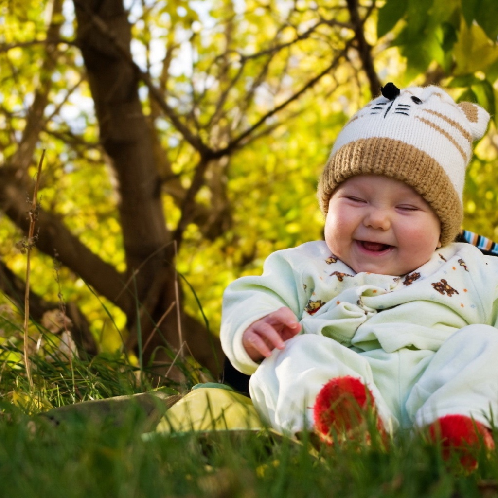 Смеющийся грудной ребенок сидит на траве