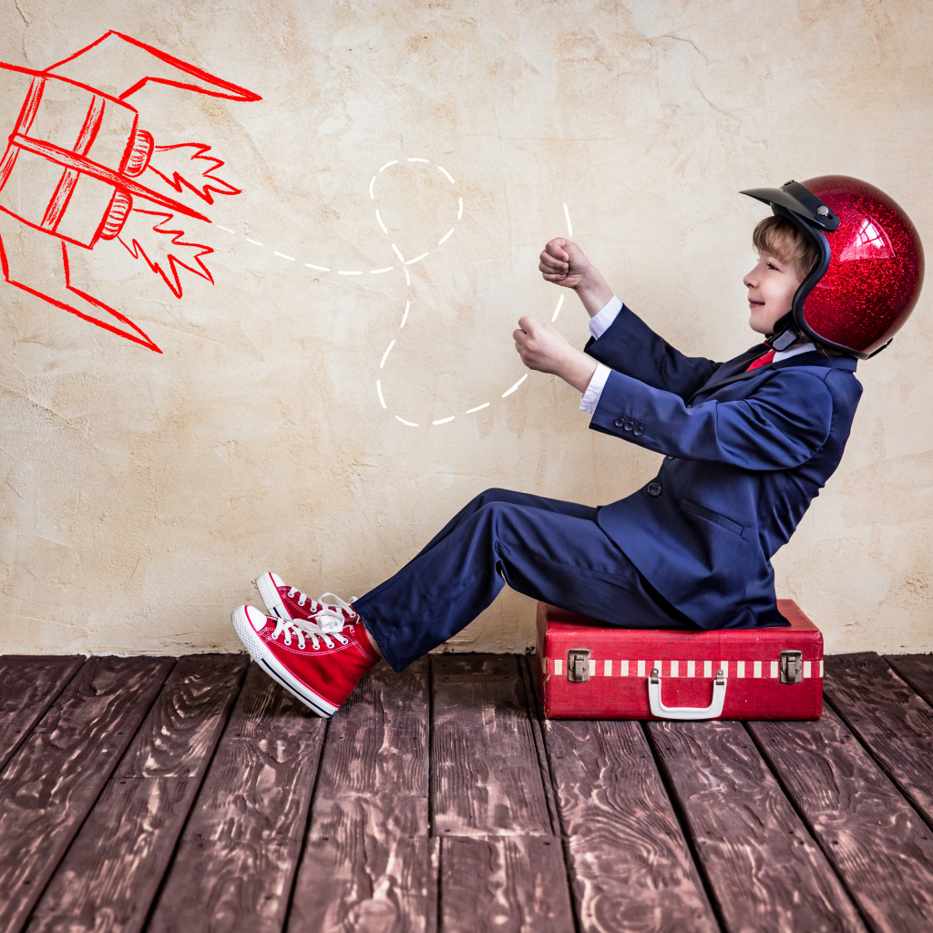 Маленький мальчик в шлеме сидит на чемодане