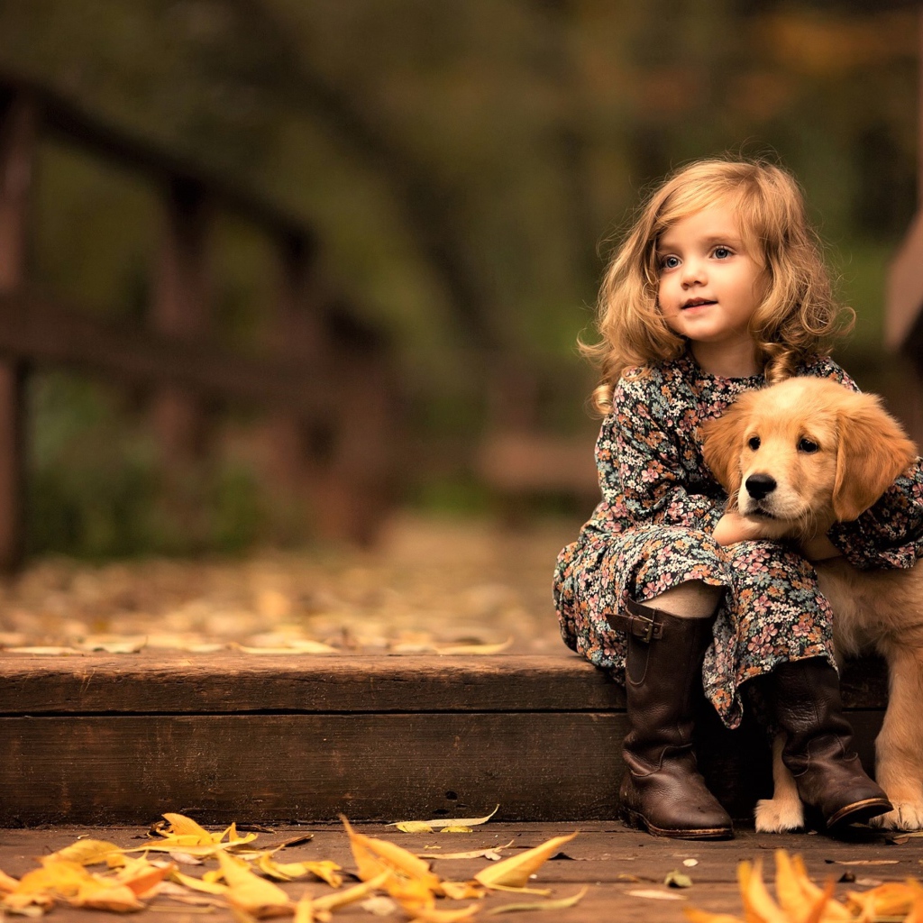 Маленькая девочка с золотистым ретривером сидит на мосту