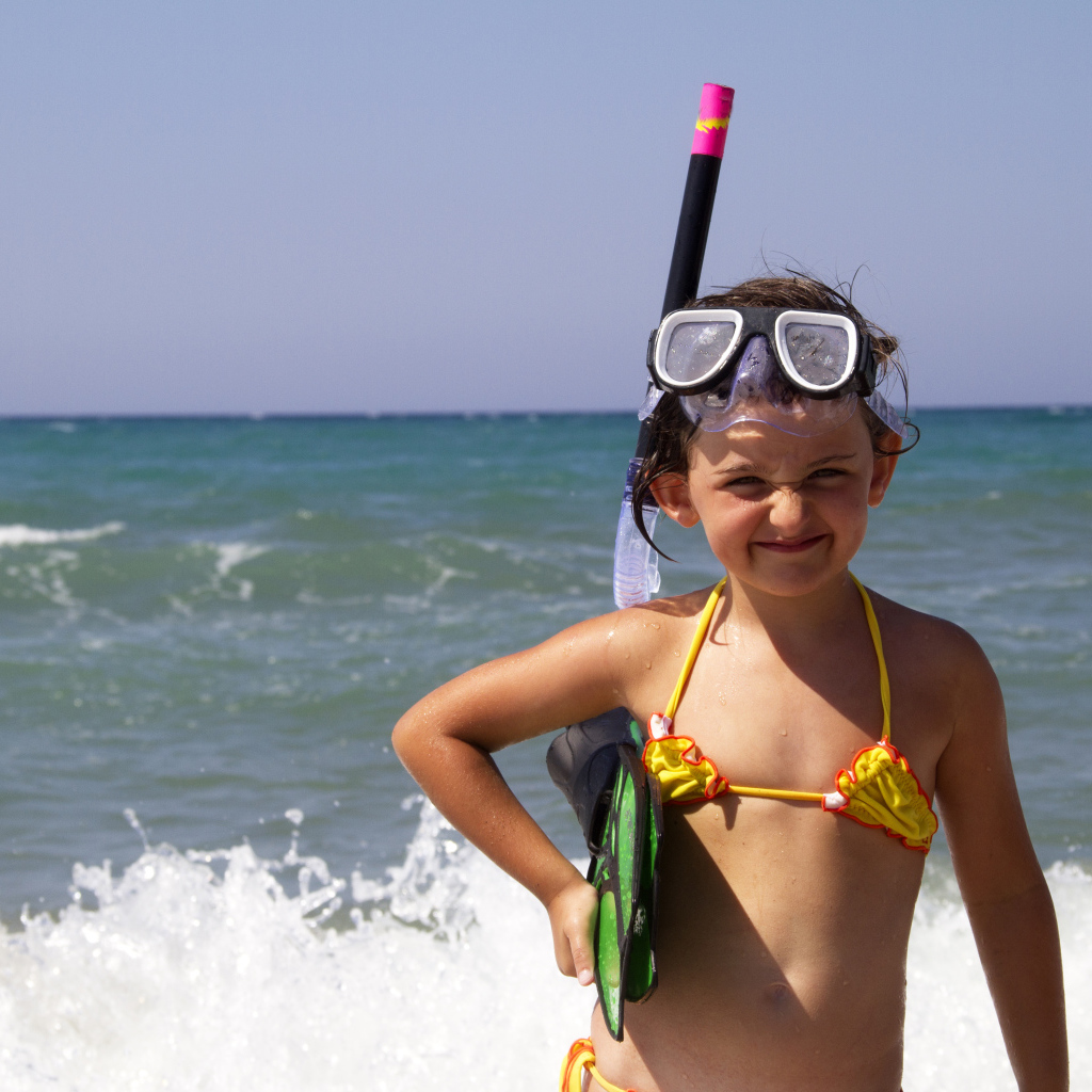 Маленькая девочка в очках и с ластами на море