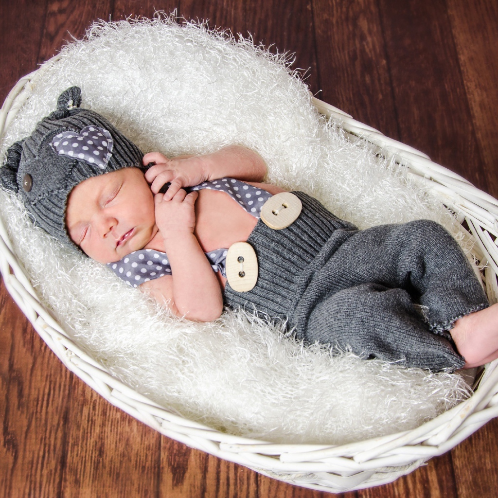 Спящий младенец в сером костюме в белой корзине
