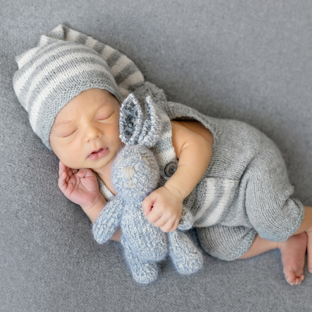 Спящий младенец с серым вязаным зайцем